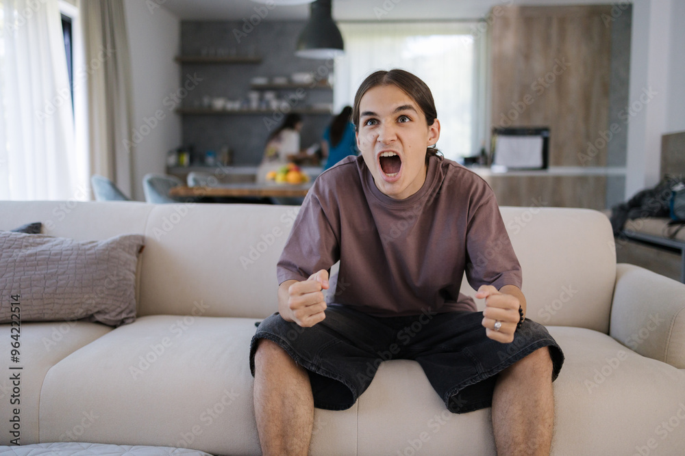 The boy watches TV and reacts emotionally to the events in the series. Boy sitting on couch at home. 