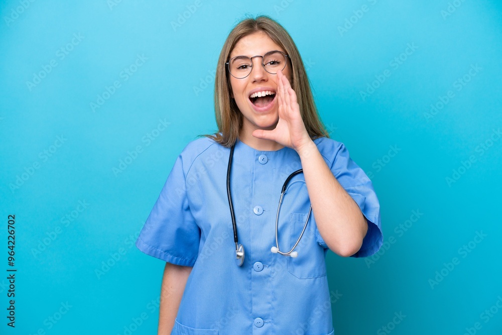 Young surgeon doctor woman isolated on blue background shouting with mouth wide open Young surgeon doctor woman isolated on blue background shouting with mouth wide open