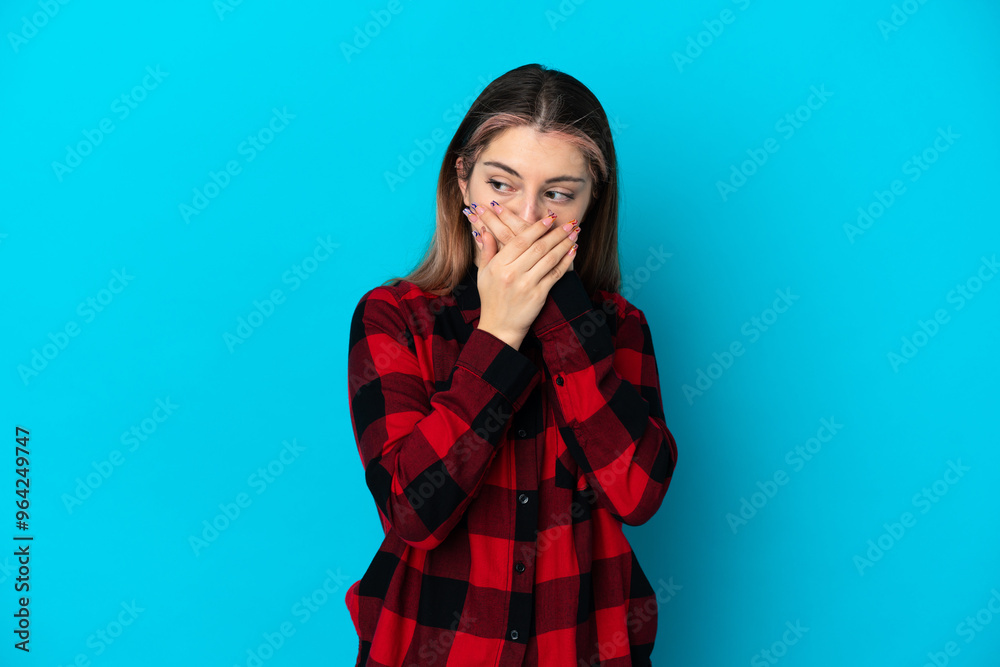 Young caucasian woman isolated on blue background covering mouth and looking to the side Young caucasian woman isolated on blue background covering mouth and looking to the side