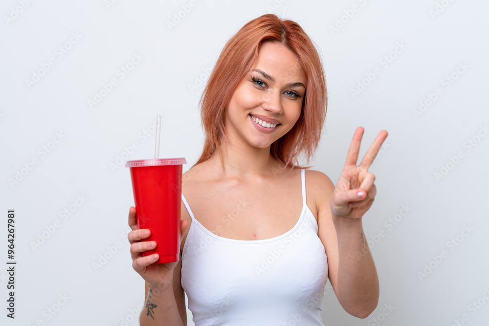 Young Russian woman holding soft drink isolated on white background smiling and showing victory sign Young Russian woman holding soft drink isolated on white background smiling and showing victory sign