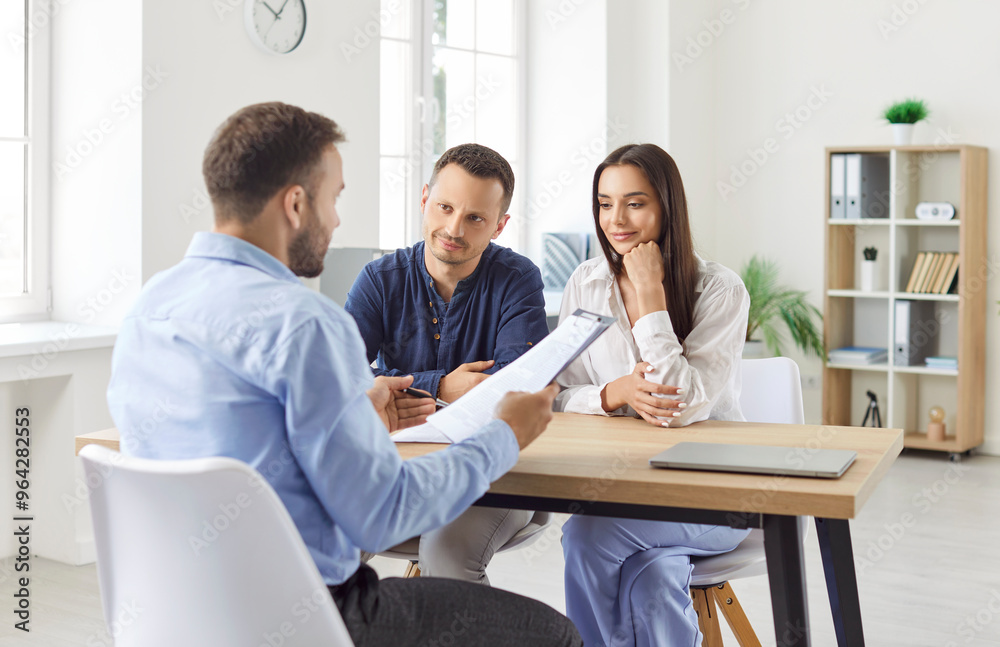 Young caucasian couple sitting at the desk discussing contract and having consultation with man realtor or financial advisor in office. Insurance agent consulting man and woman in office. Young caucasian couple sitting at the desk discussing contract and having consultation with man realtor or financial advisor in office. Insurance agent consulting man and woman in office.