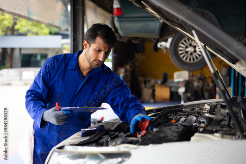 Battery inspection. Battery Capacity Tester Voltmeter. Hispanic latin man professional mechanic repairs car working in garage. Car maintenance and auto service garage concept