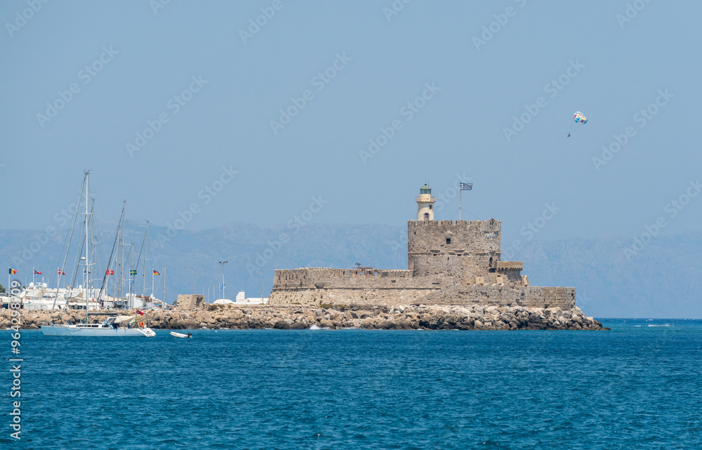 The fortress of Agios Nikolaos (Fort Saint Nicolas), a stronghold that occupies the northern tip of the jetty of the Mandraki port of Rhodes Town, Greece. The fortress of Agios Nikolaos (Fort Saint Nicolas), a stronghold that occupies the northern tip of the jetty of the Mandraki port of Rhodes Town, Greece.