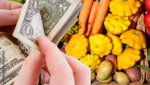 Buying food. Basket with vegetables. Money in hand. Expenses for vegetables. Man is counting dollars. Patisons and carrots in basket. Buying organic vegetables. Food with healthy vitamins photo