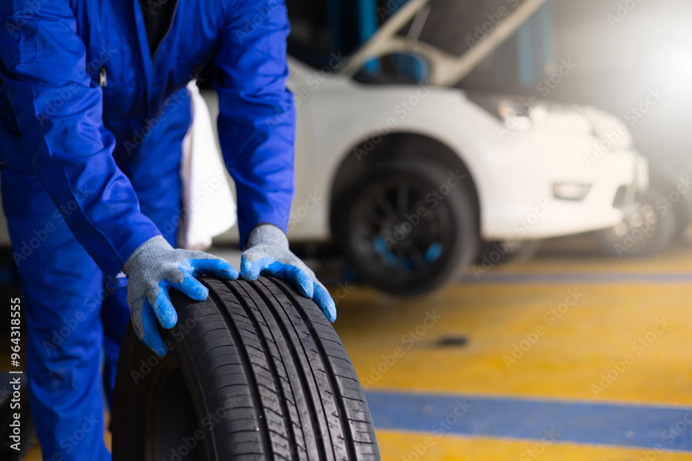Fototapeta premium Close up car tire. Mechanic man holding tire. Car maintenance and auto service garage concept