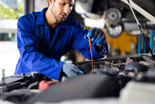 Close up hand hispanic latin male mechanic repairs car in garage. Closeup hand. Auto car mechanic checking the oil level of the car engine. Car repair and maintenance