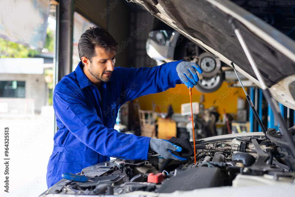 hispanic latin male mechanic repairs car in garage. Closeup hand. Auto car mechanic checking the oil level of the car engine. Car repair and maintenance hispanic latin male mechanic repairs car in garage. Closeup hand. Auto car mechanic checking the oil level of the car engine. Car repair and maintenance