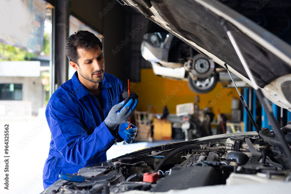 hispanic latin male mechanic repairs car in garage. Closeup hand. Auto car mechanic checking the oil level of the car engine. Car repair and maintenance hispanic latin male mechanic repairs car in garage. Closeup hand. Auto car mechanic checking the oil level of the car engine. Car repair and maintenance