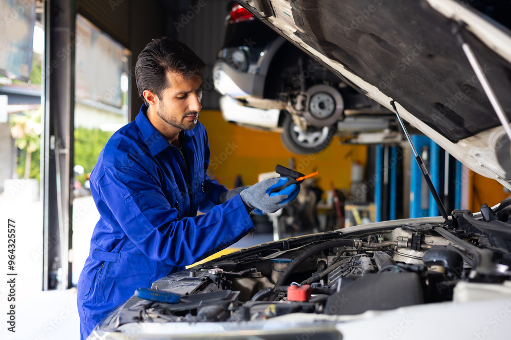 hispanic latin male mechanic repairs car in garage. Closeup hand. Auto car mechanic checking the oil level of the car engine. Car repair and maintenance hispanic latin male mechanic repairs car in garage. Closeup hand. Auto car mechanic checking the oil level of the car engine. Car repair and maintenance