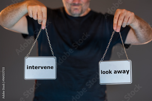 Man holding signs with the words 'intervene' and 'look away'. Symbol for the inner conflict in a dangerous situation to intervene and not look away.