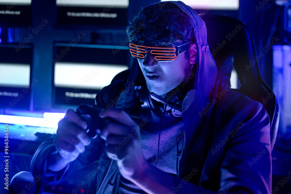 Young gamer plays computer games in a neon-lit gaming room, online e-sports streaming, focus on a specific point Young gamer plays computer games in a neon-lit gaming room, online e-sports streaming, focus on a specific point