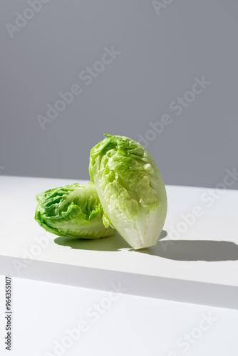 Dos corazones de lechuga romana fresca sobre una mesa blanca y fondo gris	 photo