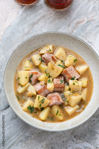 Photography Plate of dublin coddle or sausage and potato stew on a grey granite background,