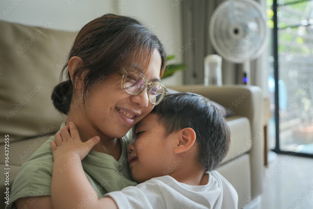 Asian mother and son are hugging. The mother is wearing glasses and the child is wearing a white shirt. Scene is warm and loving Asian mother and son are hugging. The mother is wearing glasses and the child is wearing a white shirt. Scene is warm and loving