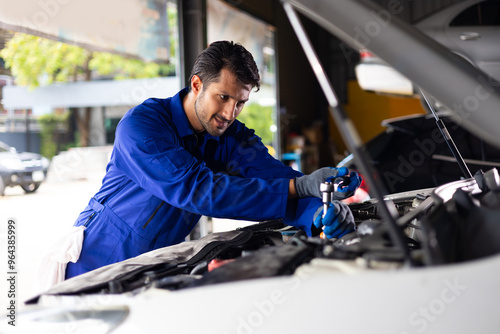 mechanical man working with tools and spanner. Hispanic latin male mechanic repairs car in garage. Car maintenance and auto service garage concept