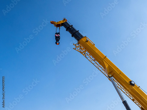 Crane boom. Construction equipment. Tower crane boom with cargo hook. Fragment of construction crane against sky. Equipment for unloading at port. Hydraulic lifting equipment on blue