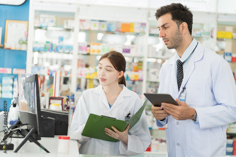 Pharmacist male and woman in white uniform inspecting list of medicine in drugs shop pharmacy Pharmacist male and woman in white uniform inspecting list of medicine in drugs shop pharmacy