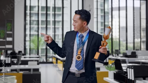 Wallpaper Mural Asian Business Man In A Suit And Tie With A Gold Medal Holding A Gold Trophy In His Hands, Smiling, And Pointing To Side In Office Torontodigital.ca