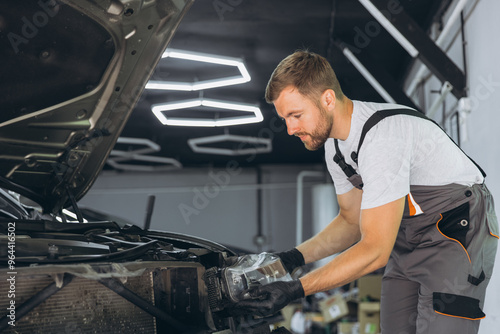 Mechanic at Work in Automotive Repair Shop Fixing Car Headlight in Garage