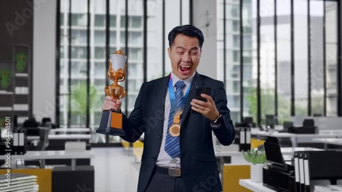Wallpaper Mural Asian Business Man In A Suit And Tie With A Gold Medal And Trophy Looking At Smartphone Then Screaming Goal Celebrating In Office Torontodigital.ca