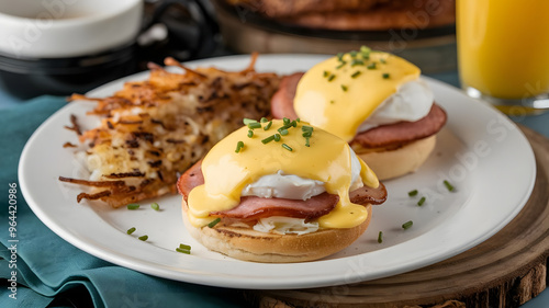 Eggs Benedict with poached eggs, Canadian bacon and hollandaise sauce on a toasted English muffin topped with chives and served with a side of home fries.