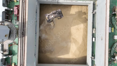 Loading dry cargo ship of wheat by cranes in port. Aerial view loading into holds of sea cargo vessel