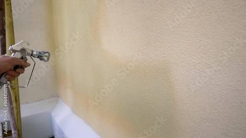 Construction worker painting wall with airless paint sprayer photo