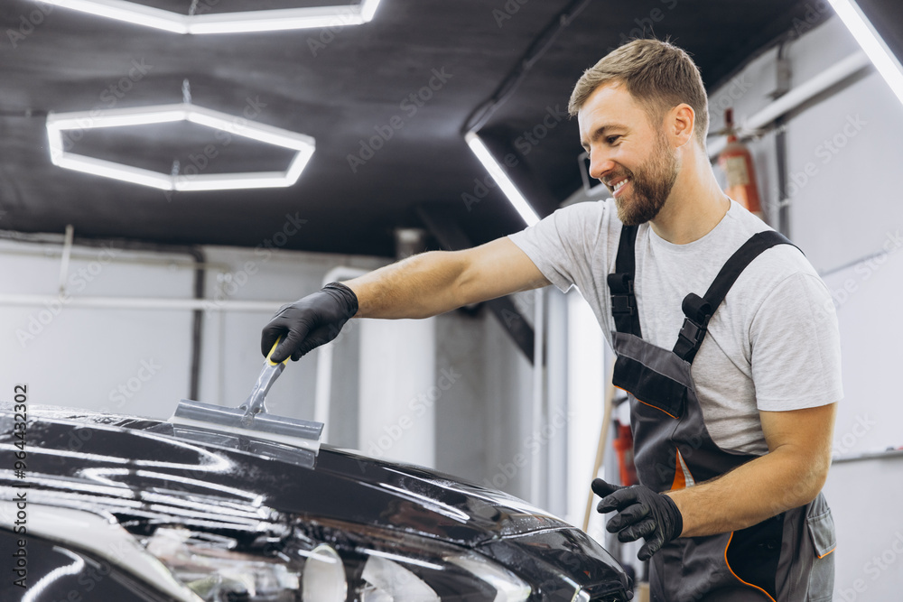Man washing car hood and preparing the polishing process Car glass coating. Male worker installing protection film to car in garage. Car Detailing. Man washing car hood and preparing the polishing process Car glass coating. Male worker installing protection film to car in garage. Car Detailing.