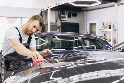 A car wrapping specialist applies a polyurethane film to the car. Selective focus. PPF protective film against chips and scratches. Car wrapping. photo