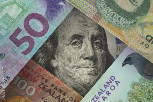 Portrait of the US President on the dollar bill peeks out from under the New Zealand dollar bills. Currency market. Finance concept