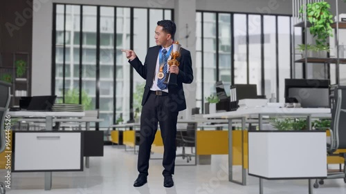 Wallpaper Mural Full Body Of Asian Business Man In A Suit And Tie With A Gold Medal Holding A Gold Trophy In His Hands, Smiling, And Pointing To Side In Office Torontodigital.ca