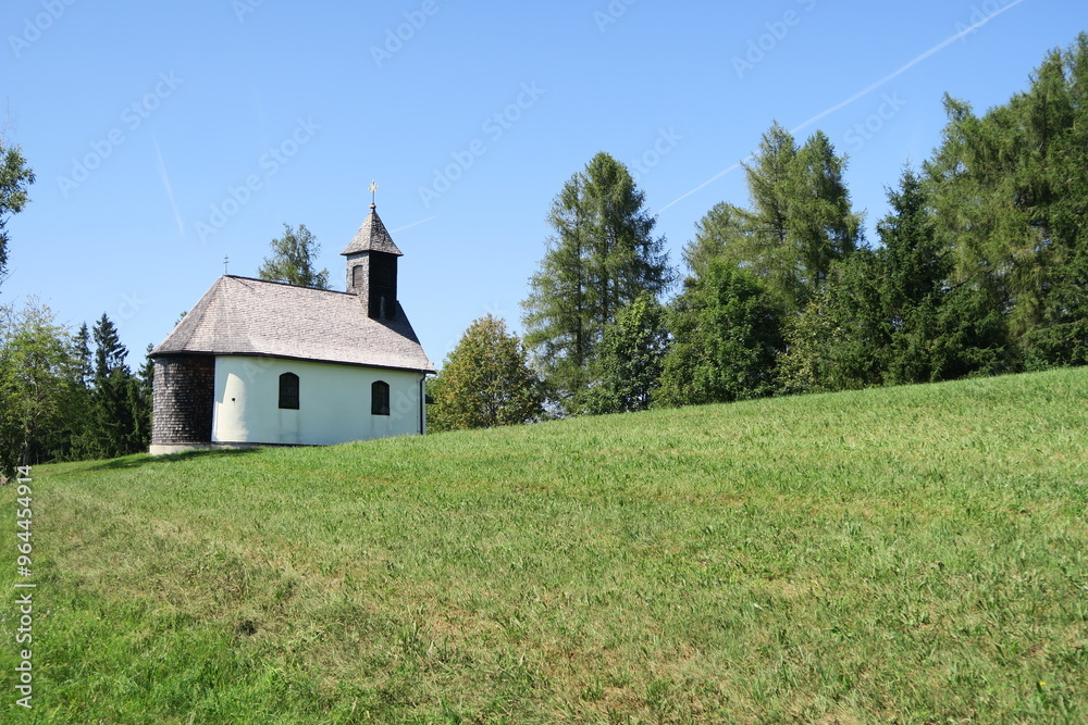 Obraz premium Auf dem Gahberg in Weyregg am Attersee steht die katholische Gahbergkapelle auf einer Wiese am Hang in Oberösterreich. Die Kapelle ist ein schönes Ausflugsziel im Sommer.