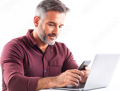 A man is sitting at a table with a laptop and a cell phone in front of him