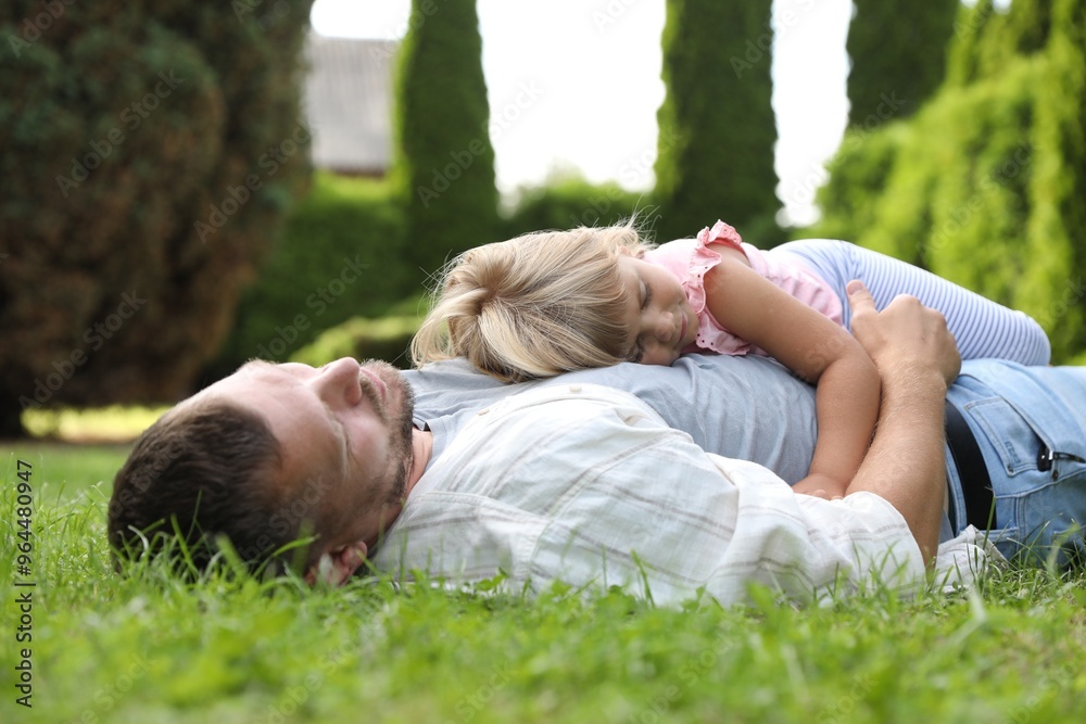 Father and his daughter spending time together on green lawn in park Father and his daughter spending time together on green lawn in park
