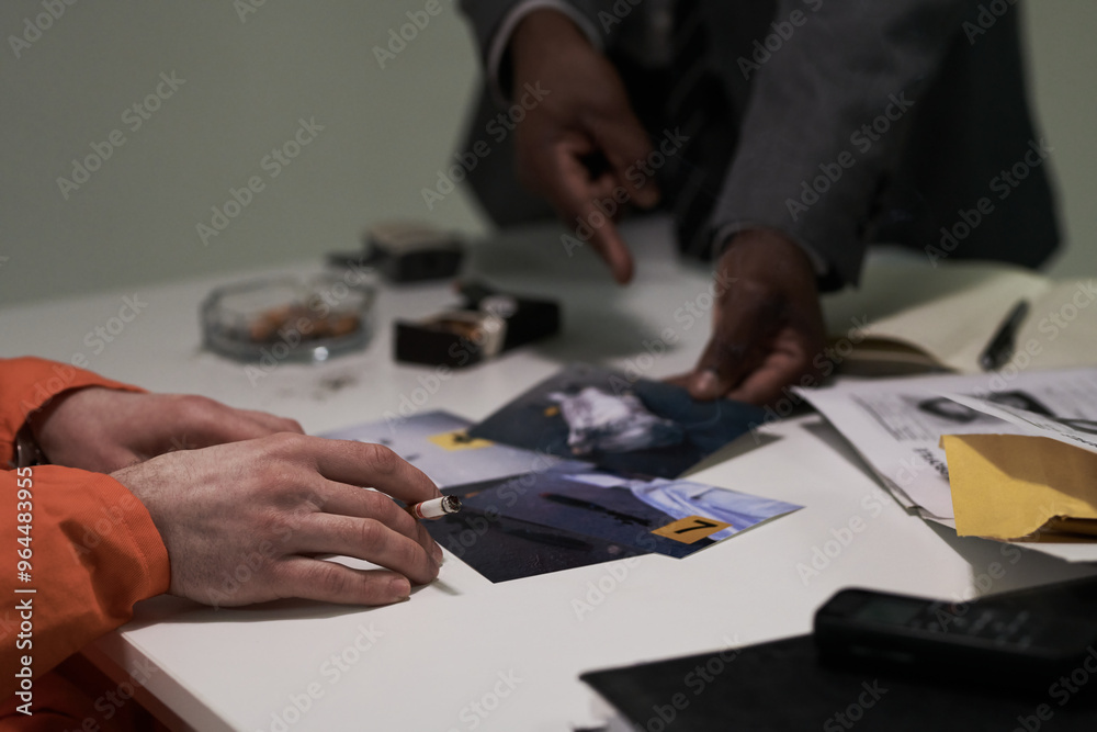 Close-up shots of hands analyzing crime scene photos on table with cigarette ashtray and evidence. Two individuals closely examining images of investigation objects Close-up shots of hands analyzing crime scene photos on table with cigarette ashtray and evidence. Two individuals closely examining images of investigation objects