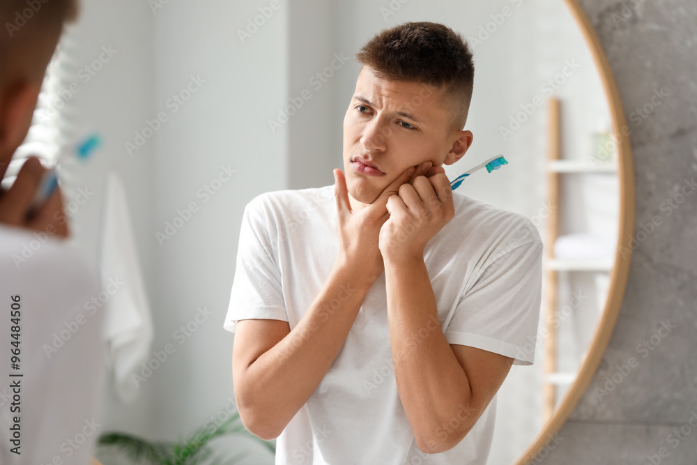 Young man with toothbrush suffering from toothache in bathroom Young man with toothbrush suffering from toothache in bathroom