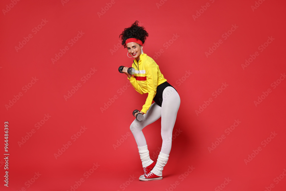 Woman doing aerobic exercise with dumbbells on red background Woman doing aerobic exercise with dumbbells on red background