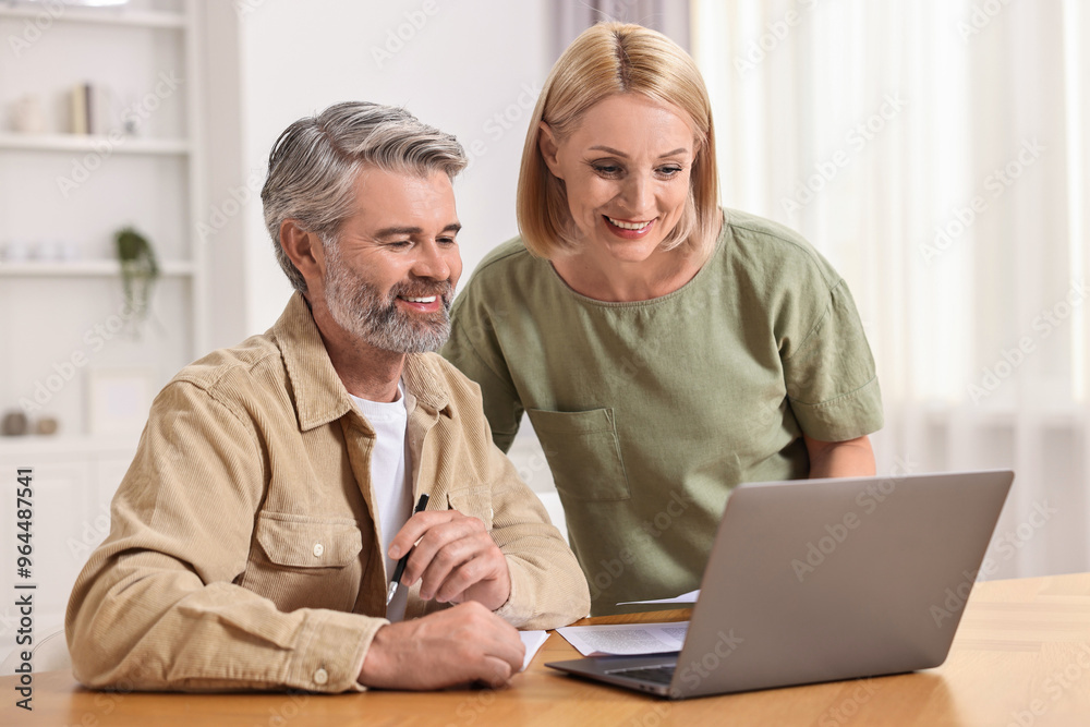 Couple planning pension budget at table indoors Couple planning pension budget at table indoors