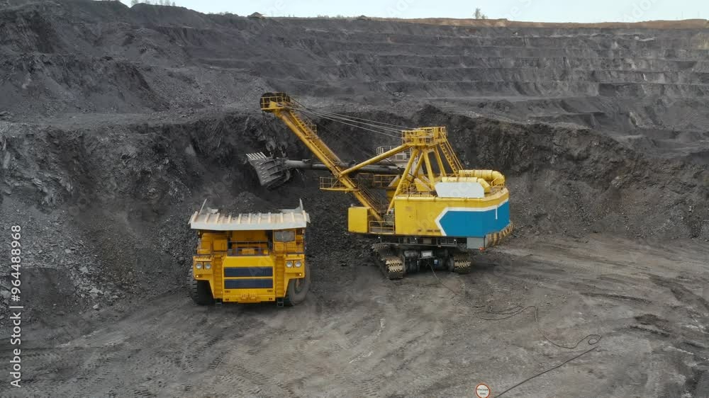 Large quarry dump truck. Loading rock in dumper. Loading coal into truck. Mining car machinery to transport coal. Open pit mine quarrying extractive industry stripping work. Big Yellow Mining Trucks Large quarry dump truck. Loading rock in dumper. Loading coal into truck. Mining car machinery to transport coal. Open pit mine quarrying extractive industry stripping work. Big Yellow Mining Trucks