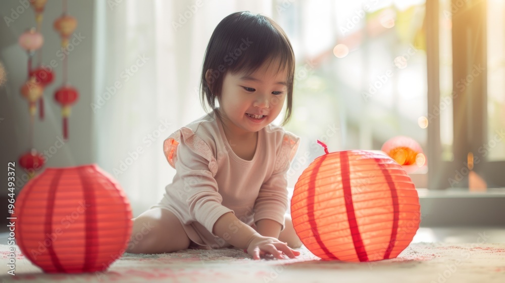 Fototapeta premium A little girl in a light-colored dress joyfully plays with illuminated red paper lanterns, celebrating in a warmly lit room filled with festive decor.