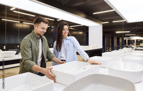 Happy family young married couple choosing a sink in a plumbing store for bathroom renovation at home. Clients are focused on finding the perfect fixture to enhance home water features.