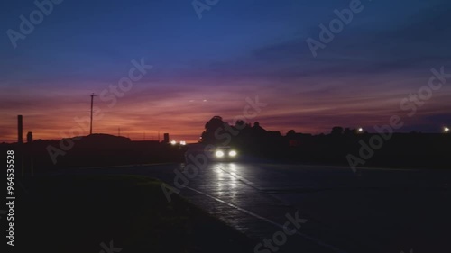 Cars crossing country road at sunset