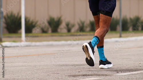 Pernas e panturrilha de um corredor durante uma corrida de rua, capturando a energia e o movimento rápido, destacando o esforço físico e a dedicação no esporte