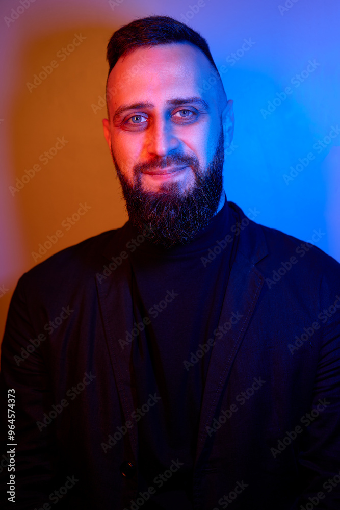 Fototapeta premium Studio portrait with colorful light of young handsome bearded man.