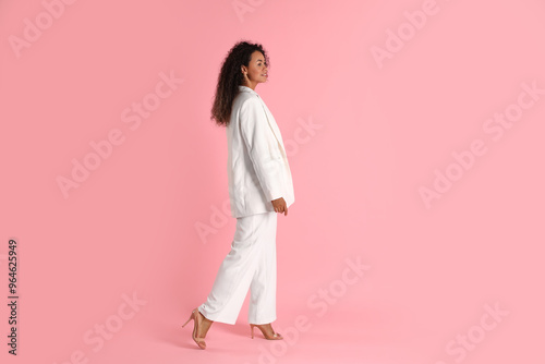 Beautiful woman in stylish suit on pink background