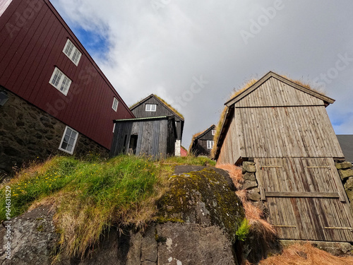 Quaint and charming rustic buildings set against atop a hill with a cloudy blue sky. Grass roof buildings. Located in Old Town Tórshavn, the capital city of the Faroe Islands on the island of Streymoy