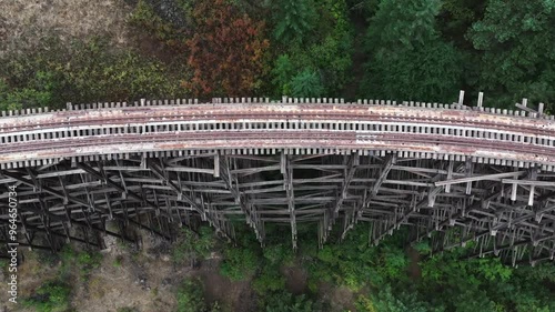 Curved wooden train trestle in a forested photo