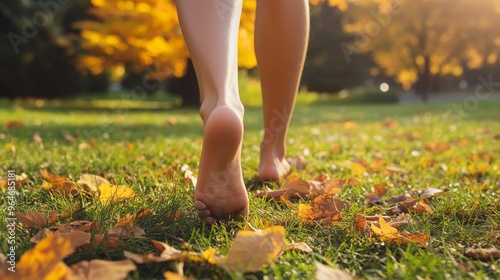 Barefoot Woman Walking on Grass Covered With Autumn Leaves in a Sunlit Park photo