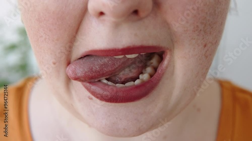 European woman with open mouth moves tongue from side to side close up. Person tongue movement and articulatory gymnastics with muscle movement. photo