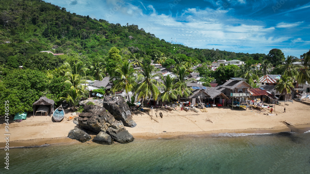 Naklejka premium Aerial view of Nosy Komba Island showcasing lush greenery, sandy beaches, and traditional dwellings along the coastline